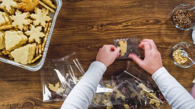 Düz yatıyordu. Dikkatlice paketlenmiş Noel kurabiyeleri, çikolataya batırılmış, ezilmiş fındık serpiştirilmiş, ve şeffaf selofan ambalajla sunulmuş..