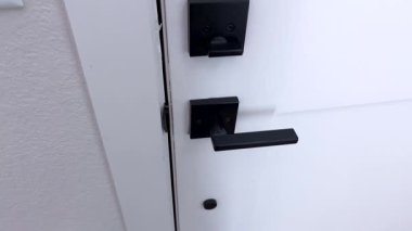 Bir kişinin eli, fırçalanmış metal bir kapı kulpu kullanılarak bir odaya girme ya da çıkma eylemini gösteren bir kapı açma işlemi sırasında yakalanır..