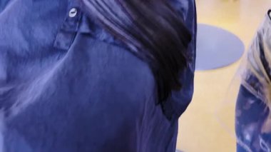 Salonun hareketli atmosferinde, küçük bir kız sabırla oturur. Cilalı kırmızı tırnakları nemli saçlarını dikkatlice kesen bir stilist gibi. Makas parıltısı ve hassas el hareketleri yakalar.