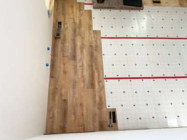 Broomfield, Colorado, ABD-26 Ocak 2025. Oturma odasının zemin döşeme kurulumunun en yukarıdan görünüşü. Bir bölüm yeni döşenmiş ahşap döşeme, diğer taraf ise hala alt katmanlı.