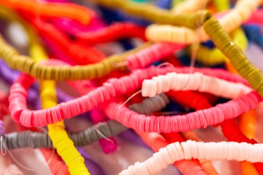 Beyaz bir masadaki renklere göre düzenlenmiş canlı bir kil boncuk koleksiyonu genç zanaatkarlara kendi eşsiz bileziklerini yapmaları için ilham vermeye hazır..