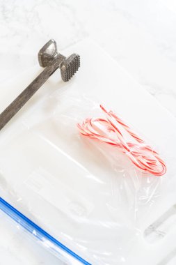 Castle Rock, Colorado, USA-November 26, 2024-A flat lay of uncrushed candy canes in a sealed plastic bag alongside a metal meat tenderizer, ready for crushing to prepare for holiday baking projects. clipart