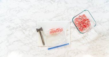 Castle Rock, Colorado, USA-November 26, 2024-Flat lay of crushed candy canes in a bag, with the mallet and container of whole candy canes displayed on a marble surface clipart