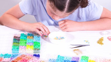 Genç bir kızın narin parmakları parlak, renkli boncuklardan oluşan bir hazinede geziniyor. Her bölümde seçilecek yeni bir renk var..