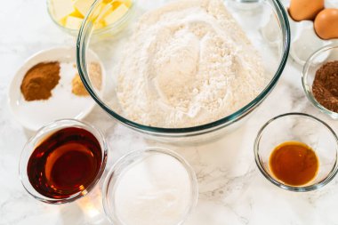 İçinde un, tereyağı, yumurta, esmer şeker, akçaağaç şurubu, kakao ve baharat bulunan Ginger Şekerli Kurabiye Hamuru 'nun içeriğinin tamamı mermer bir yüzeye yerleştirilmiş..