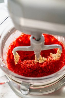 Akçaağaç pekmezi ve yumurta karışımı karıştırma kabındaki kremalı tereyağı ve kahverengi şekere eklenir. Islak malzemeler harmanlanarak Klasik Kızıl Zencefilli Çörek için canlı bir temel oluşturuyor..