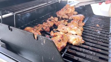 Salamura edilmiş tavuk butları küçük bir Weber ızgarasının ızgarasında cızırdar, havayı iştah açıcı bir koku ve hafif bir dumanla doldurur..