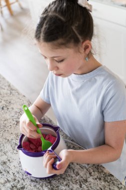 Odaklanmış bir dikkatle, bu filizlenen aşçılık sanatçısı krakerleri erimiş çikolataya batırarak iyi aydınlatılmış bir ev mutfağının sıcaklığında tatlı tatlar yaratıyor..