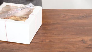 Tuzlu karamel şekerlemeleri ve zencefilli ekmek parçacıklarıyla süslenmiş zencefilli keki dikkatlice hediye etmek için açık pencereli beyaz bir kağıt bohça kek kutusuna yerleştiriyorum..