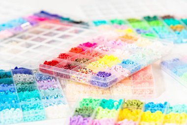 Beyaz bir masaya yerleştirilmiş çeşitli kil boncuk kutuları yaratıcı çocukların el sanatları projesini bekliyor..