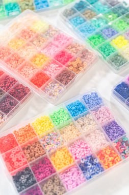 Beyaz bir masaya yerleştirilmiş çeşitli kil boncuk kutuları yaratıcı çocukların el sanatları projesini bekliyor..