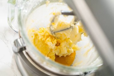 Karıştırıcı kremalı tereyağı, şeker ve klasik şekerli kurabiye hamuru için bir yumurta. Malzemeler kısmen harmanlanmış, kabarık, kremsi dokuyu vurguluyor.