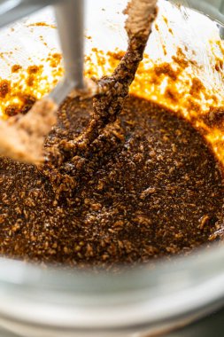 Tereyağlı şeker karışımına pekmez karıştıran bir tezgahın yukarıdan görünüşü Baharatlı Zencefilli Kurabiye Kurabiyesi için mükemmel bir temel oluşturuyor. Karışım pürüzsüz ve karanlık.