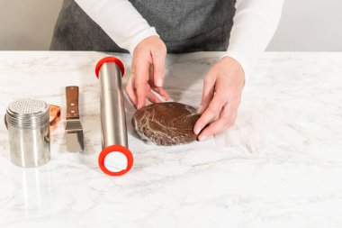 Çikolatalı zencefilli ekmeğin ambalajını mermer bir yüzey üzerinde açarken, fırın aletleri ve eldiven şeklindeki kesiciyle....