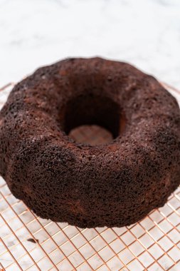 Chocolate Bundt Pastası dikkatlice tavadan çıkartılır. Yuvarlak soğutma rafına yerleştirilir. Kusursuz bir sunum ve hoş bir hoşgörü için hazırlanır..