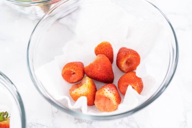 Taze yıkanmış ve kurutulmuş çilekler kağıt havluyla kaplı cam bir kasede dikkatlice düzenlenir. Atıştırmaya ya da daha fazla kullanılmaya hazır hale getirilir..