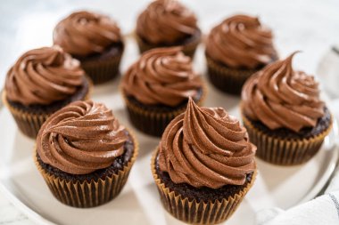 Taze pişmiş kekler ustaca zengin karamel ile dolduruldu ve kadife çikolatalı şekerlemeyle süslendi. Hepsi de el değmemiş beyaz servis tabağında zarif bir şekilde sunuldu..