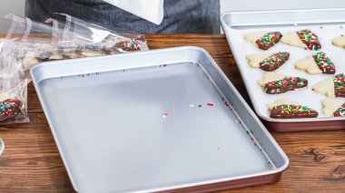 Dikkatlice paketlenmiş Noel kurabiyeleri, çikolataya batırılmış ve şeffaf selofan ambalajla sunulmuş, bayram hediyesi olarak mükemmel..