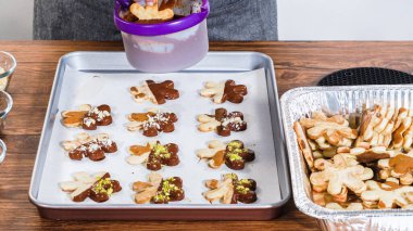 Çikolataya batırılmış ve çeşitli malzemeler serpiştirilmiş yıldız şeklinde tatil kurabiyeleri..