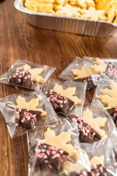 Dikkatlice paketlenmiş Noel kurabiyeleri, çikolataya batırılmış ve şeffaf selofan ambalajla sunulmuş, bayram hediyesi olarak mükemmel..