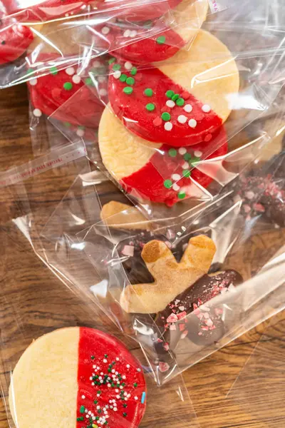 Dikkatlice paketlenmiş Noel kurabiyeleri, çikolataya batırılmış ve şeffaf selofan ambalajla sunulmuş, bayram hediyesi olarak mükemmel..