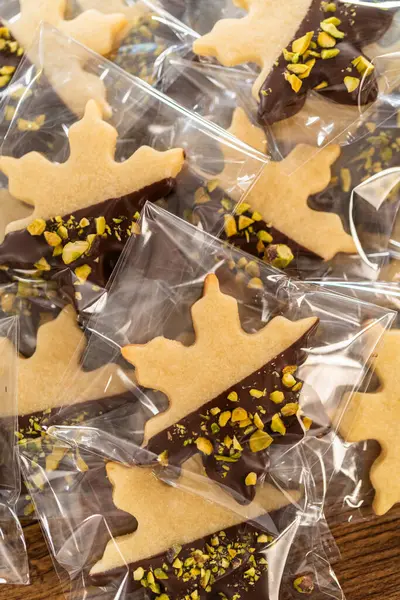 Dikkatlice paketlenmiş Noel kurabiyeleri, çikolataya batırılmış ve şeffaf selofan ambalajla sunulmuş, bayram hediyesi olarak mükemmel..