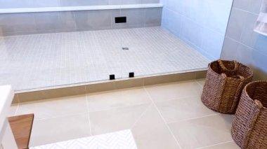 Bu resim iyi tasarlanmış bir duş alanı yakalar, bej kaplamalı döşeme tezgahı kaplar, parlak bir drenaj sistemi, ve minimalist cam kapılar, temiz ve modern bir sunar.