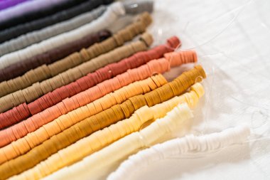 Beyaz bir masadaki renklere göre düzenlenmiş canlı bir kil boncuk koleksiyonu genç zanaatkarlara kendi eşsiz bileziklerini yapmaları için ilham vermeye hazır..