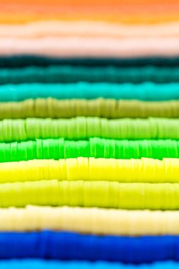 Beyaz bir masadaki renklere göre düzenlenmiş canlı bir kil boncuk koleksiyonu genç zanaatkarlara kendi eşsiz bileziklerini yapmaları için ilham vermeye hazır..