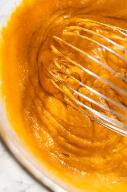 Ağız sulandırıcı ev yapımı balkabağı pastası için büyük bir karıştırma kabında ustalıkla harmanlanmış malzemelerin yakın çekimi..