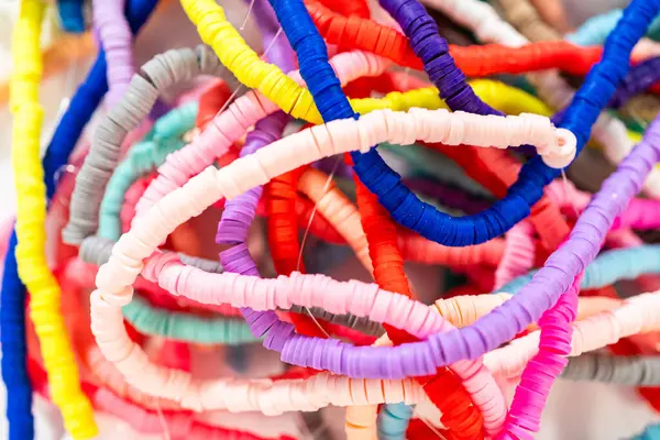 Beyaz bir masadaki renklere göre düzenlenmiş canlı bir kil boncuk koleksiyonu genç zanaatkarlara kendi eşsiz bileziklerini yapmaları için ilham vermeye hazır..