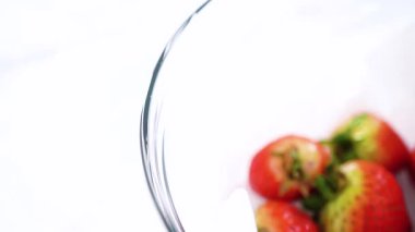 Olgun çilekler, depolama veya tüketimden önce temizlik ve uzun ömürlü olmak için meyveyi yıkamada bir adım olarak büyük bir bardakta karıştırma kabında suya gömülür..