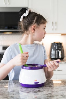 Odaklanmış bir dikkatle, bu filizlenen aşçılık sanatçısı krakerleri erimiş çikolataya batırarak iyi aydınlatılmış bir ev mutfağının sıcaklığında tatlı tatlar yaratıyor..