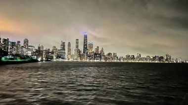 Chicago, Illinois, ABD-Kasım 7, 2023 - Chicago şehir merkezinin büyüleyici gece manzarası gölün sakin sularından görüldüğü gibi.
