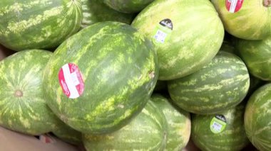 Colorado Springs, Colorado, ABD-13 Mayıs 2024 Sams Club 'da canlı, olgun karpuz gösterisi. Her birinin kalitesini gösteren bir çıkartması olan karpuzlar üst üste yığılmıştır.