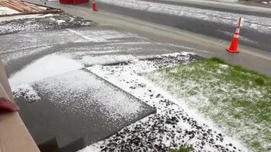 Castle Rock, Colorado, ABD-9 Haziran 2024-Ağır çekim-A varoş mahallesi modern evler fırtınadan sonra dolu tabakasıyla kaplandı. Olay yerinde park etmiş bir araba ve cadde var.