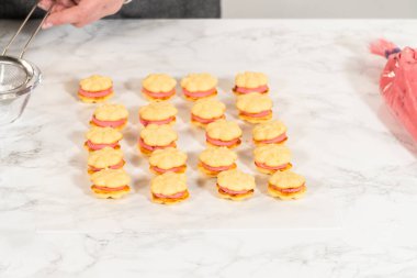 Çok güzel dekore edilmiş limon spreyli kurabiyeler kızılcık kreması ile doldurulmuş ve üzerinde mükemmel pipo kıvrımları var. Bu hareketli ikramlar tatil toplantıları veya hediyeler için idealdir.