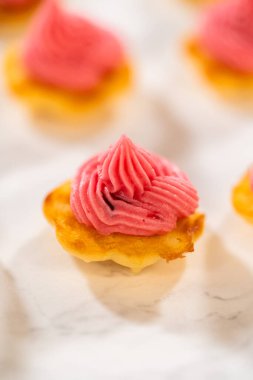 Üstünde kızılcık kreması olan taze pişmiş limonlu spritz kurabiyeler. Canlı pembe dolgu, altın kurabiye tabanıyla çok güzel tezat oluşturuyor. Zarif bir tatlı oluşturuyor.