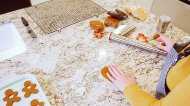 Modern bir mutfaktaki zarif mermer tezgahın üzerine zencefilli kurabiye hamuru sermek için ayarlanabilir bir merdane kullanmak, bayram pişirme şenliğine hazırlanmak....