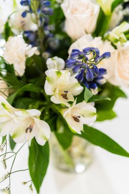 Taze beyaz güllerin ve çeşitli çiçeklerin bulunduğu büyüleyici bir buket, zarif bir vazoda düzenlenmiş, zamansız bir güzellik yayıyor..