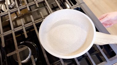 İki mükemmel kızarmış güneşli yumurta çubuksuz bir tavada oturur, kırmızı silikon bir spatula servis etmeye hazırdır, hepsi ocağın tepesinde..