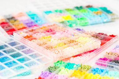 Beyaz bir masaya yerleştirilmiş çeşitli kil boncuk kutuları yaratıcı çocukların el sanatları projesini bekliyor..