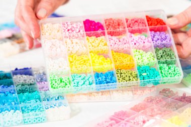 Beyaz bir masaya yerleştirilmiş çeşitli kil boncuk kutuları yaratıcı çocukların el sanatları projesini bekliyor..