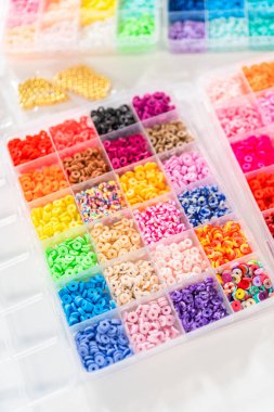 Beyaz bir masaya yerleştirilmiş çeşitli kil boncuk kutuları yaratıcı çocukların el sanatları projesini bekliyor..