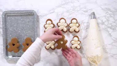 Düz yatıyordu. Zencefilli kurabiyeler mermer yüzeyde ikinci yarılarını beklerler, her biri lezzetli sandviçler yapmak için tereyağlı kremayla titizlikle borular. Boruların hassasiyeti şenlik katıyor.