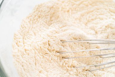 Klasik Şekerli Kurabiye Hamuru, un ve şeker de dahil olmak üzere kuru malzemelerin yakın çekim görüntüsü kasede dokulu bir karışım gösteriyor. Bu makro atış un dokusunun ince detaylarını yakalar.