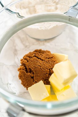 Kahverengi şeker ve tereyağı küpleri içeren cam karıştırma kabının yakından görüntüsü, Amber zencefilli kurabiye kurabiye kurabiye tarifinde krema için hazırlandı..