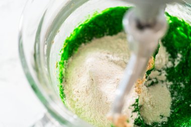 Karıştırıcıdaki yeşil karışıma Vibrant Green Zencefilli Kurabiye 'nin hamurunu tamamlamak için katılmış kuru malzemeler. Un, baharat ve yeşil karışım şenlikli bir hamur yaratıyor..