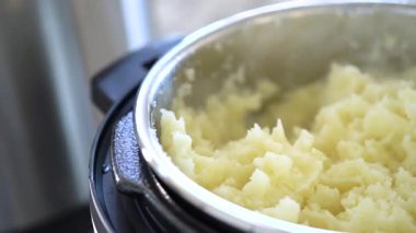 Şık, modern bir mutfakta, hızlı ve lezzetli bir yemek için fırın kullanarak kadifemsi patates püresi hazırlıyor..