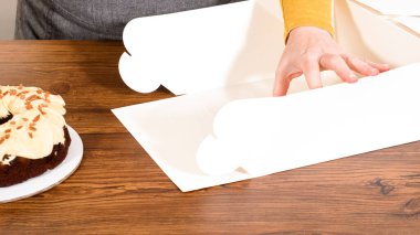 Tuzlu karamel şekerlemeleri ve zencefilli ekmek parçacıklarıyla süslenmiş zencefilli keki dikkatlice hediye etmek için açık pencereli beyaz bir kağıt bohça kek kutusuna yerleştiriyorum..